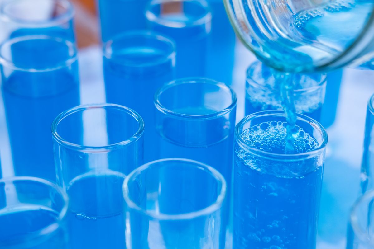 Tubo de ensaio com líquido azul em laboratório de análises